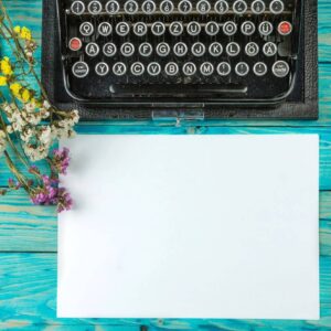 A typewriter with paper and flowers on the table.