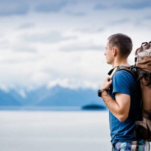 A man with a backpack standing on the beach.