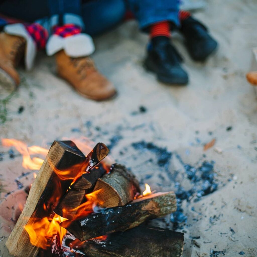 A fire is burning on the ground with people sitting around it.