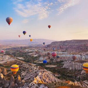A group of hot air balloons flying over the mountains.