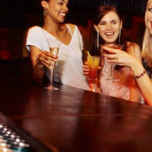 Three women are drinking at a bar.